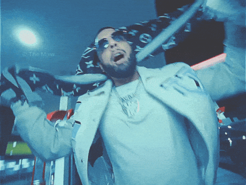 a man wearing sunglasses and a louis vuitton scarf is dancing