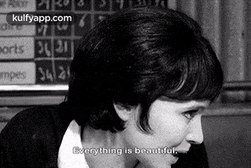a black and white photo of a woman sitting in front of a scoreboard with the words `` everything is beautiful '' .
