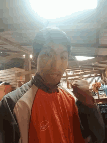 a man wearing an orange jacket with a white logo on the front