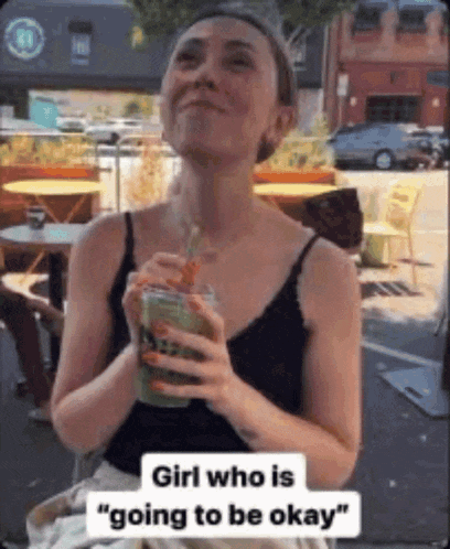a woman in a black tank top is drinking a green smoothie with a straw .