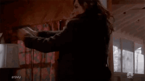 a woman is holding a gun in front of a nbc sign