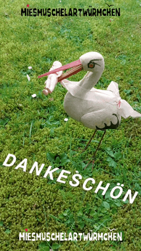 a statue of a stork holding a baby in its beak with the words dankeschon on the bottom