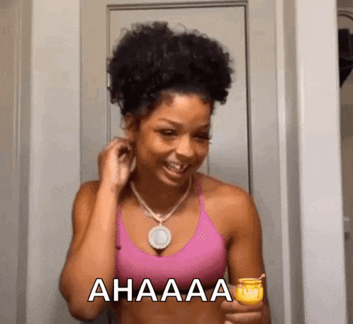 a woman in a pink tank top is smiling and holding a candle .