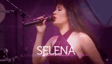 a woman is singing into a microphone on stage .