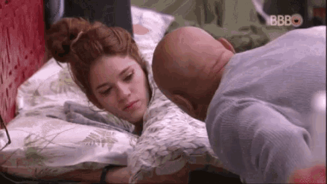 a man and a woman are laying on a bed and the man is touching the woman 's arm .