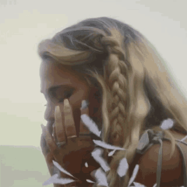 a woman with braided hair is covering her mouth with her hand