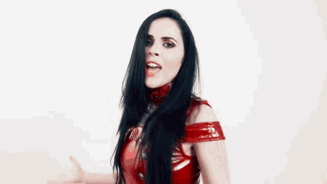a woman with long black hair is wearing a red leather top