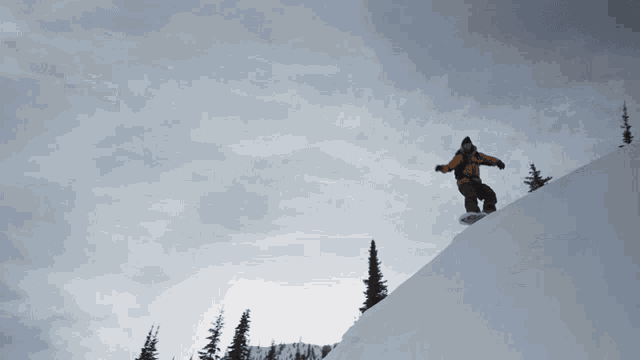 a snowboarder is riding down a snowy slope with trees in the background