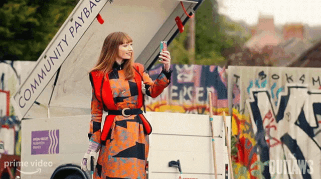 a woman taking a selfie in front of a community payback truck