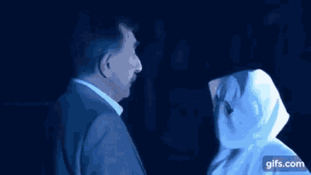 a man and a woman are looking at each other in a dark room .