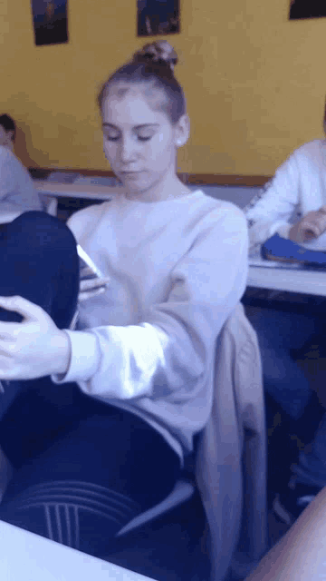 a girl is sitting at a table looking at her cell phone
