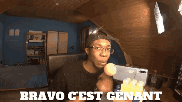 a man in a room with bravo c'est genant written in white