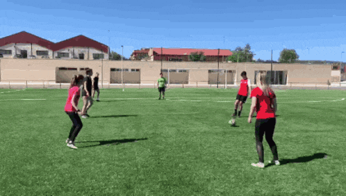 a group of people are playing soccer on a field with a building in the background