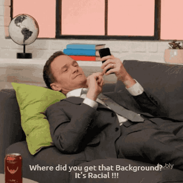 a man in a suit is laying on a couch and looking at his phone