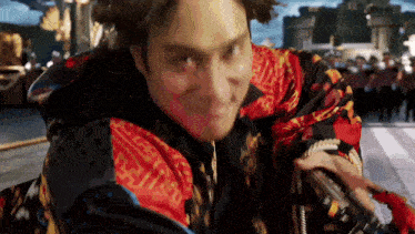 a man wearing a colorful jacket is holding a sword