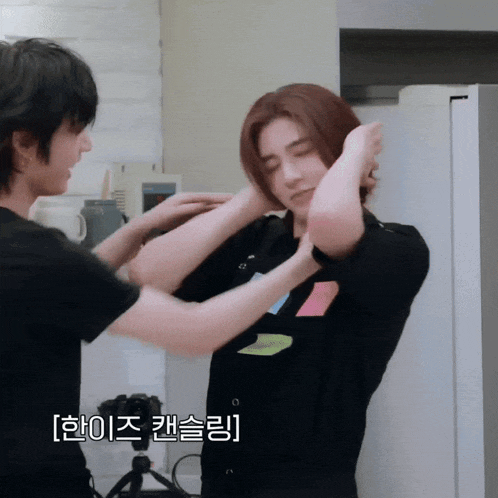 a man is putting a sticky note on another man 's shirt