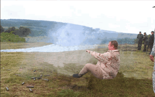 a man is laying on the ground in a field with smoke coming out of it