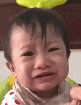 a baby is crying and making a funny face while being held by a person .