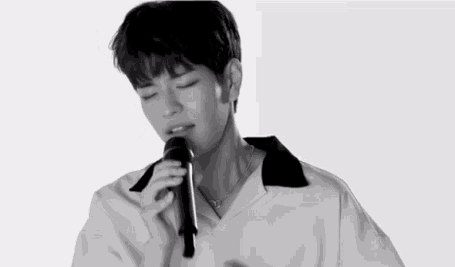 a young man is singing into a microphone with his eyes closed