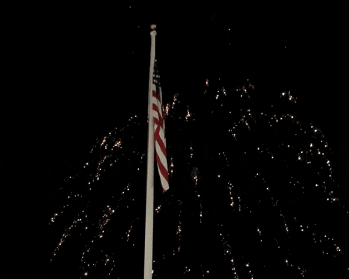 fireworks are displayed in front of the american flag
