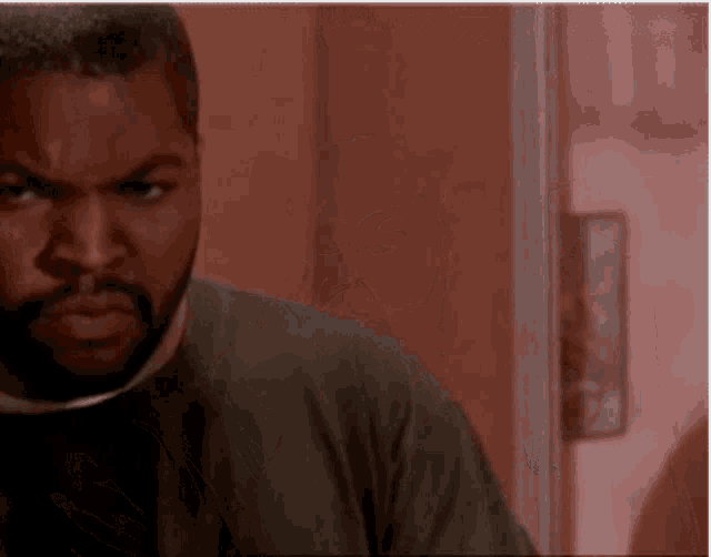 a man with a beard is standing in a room looking at the camera .