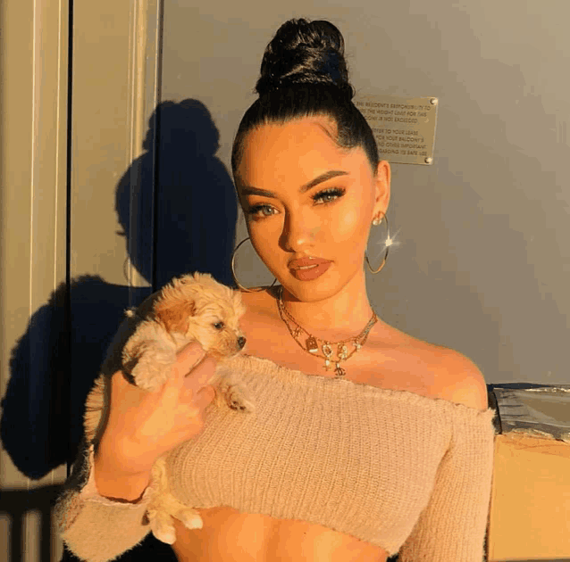 a woman is holding a small puppy in front of a sign that says " no pets allowed " on it