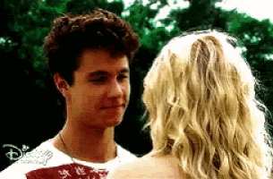 a man and a woman are looking at each other . the man is wearing a disney shirt .