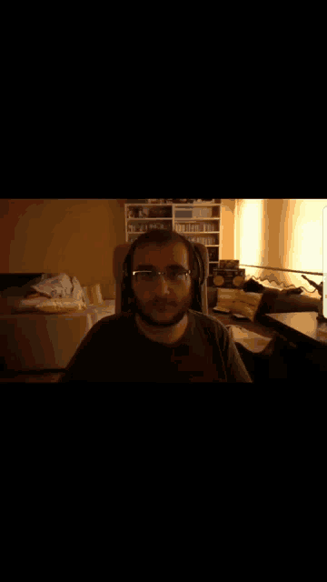 a man with glasses and a beard is wearing headphones and looking at the camera