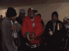 a man in a red jacket is dancing in a room with other people .