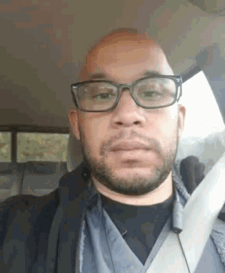 a bald man with glasses and a beard is sitting in a car