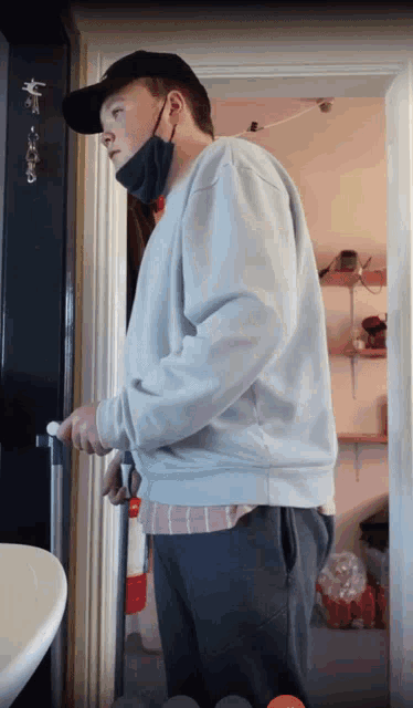 a man wearing a mask and a hat is standing in front of a door