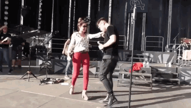 a man and a woman are dancing on a stage in front of a sign that says a
