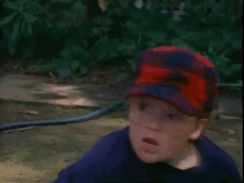 a young boy wearing a baseball cap is making a funny face .