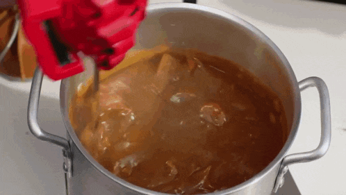 a pot of stew is being stirred with a red mixer
