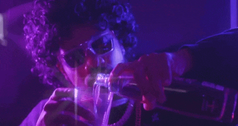 a man is pouring a drink into a glass while wearing sunglasses .