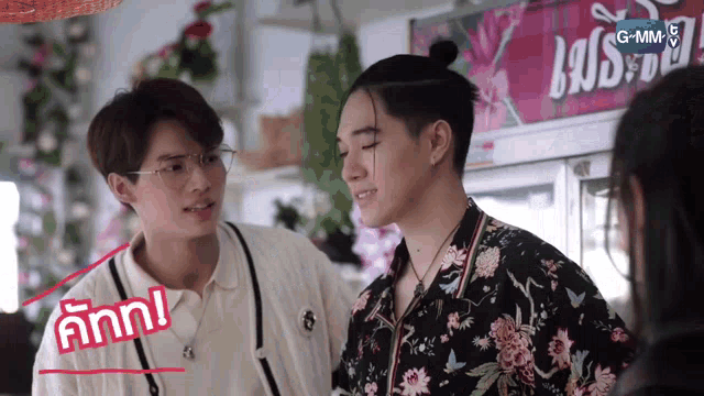 two men are standing next to each other in front of a sign that says g + mm