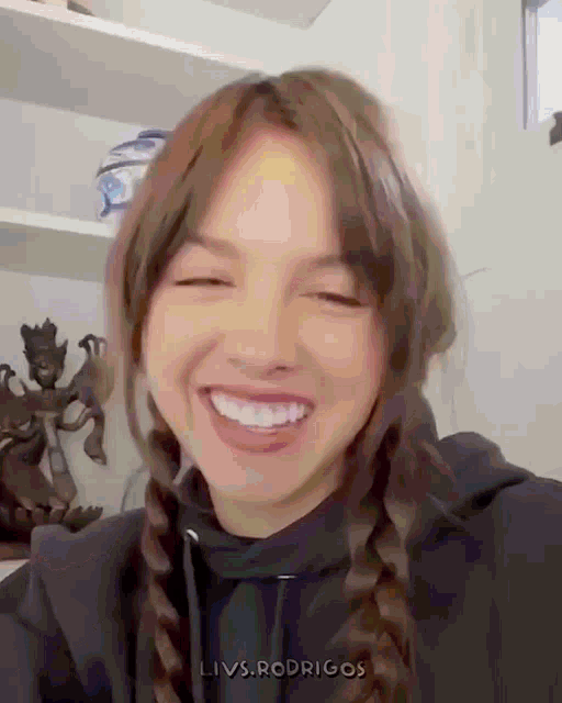 a girl with braids is smiling and wearing a black hoodie