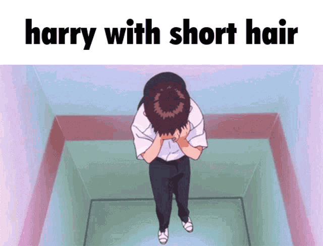 a man with short hair is standing in a corner with his head in his hands