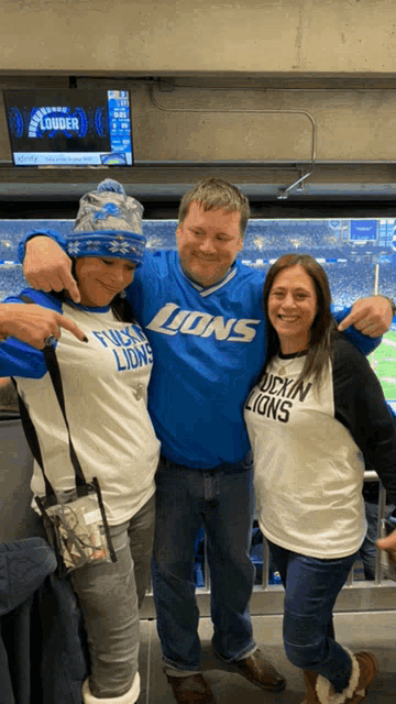 a man wearing a lions jersey stands between two women