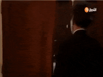 a man in a suit is holding a bouquet of flowers in front of a tv screen .