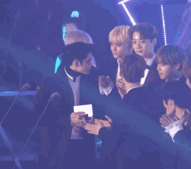 a group of men are standing in front of microphones and one of them is holding a card that says ' a ' on it