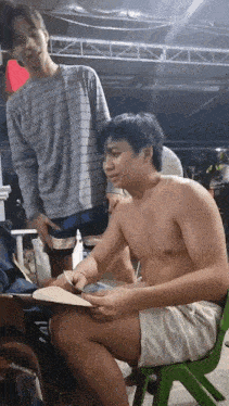 a man without a shirt is sitting in a green chair