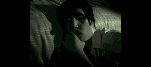 a woman is laying on a bed with her hand on her face .