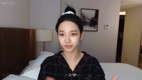 a woman in a plaid shirt is standing in front of a bed