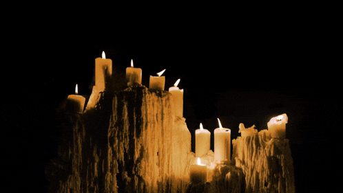 a row of lit candles against a dark background