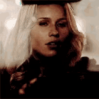 a close up of a woman wearing a hat and holding a gun .