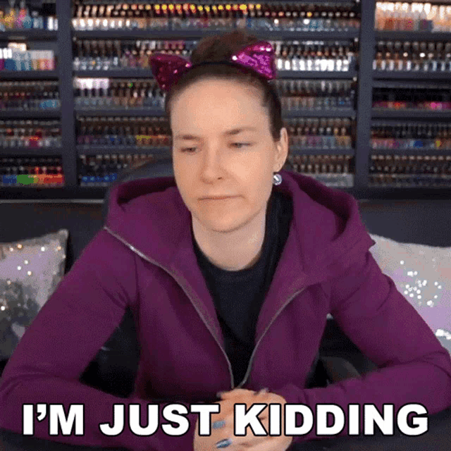 a woman in a purple jacket says i 'm just kidding while wearing a cat ear headband