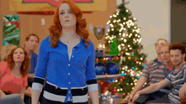 a woman stands in front of a christmas tree