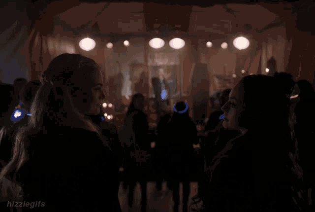 two women are standing next to each other in a dark room with the words " zziegiis " on the bottom