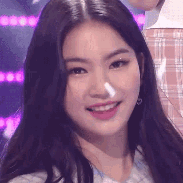 a close up of a woman 's face with a plaid shirt behind her